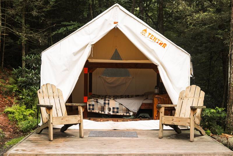White safari tent on a wooden deck with two Adirondack chairs