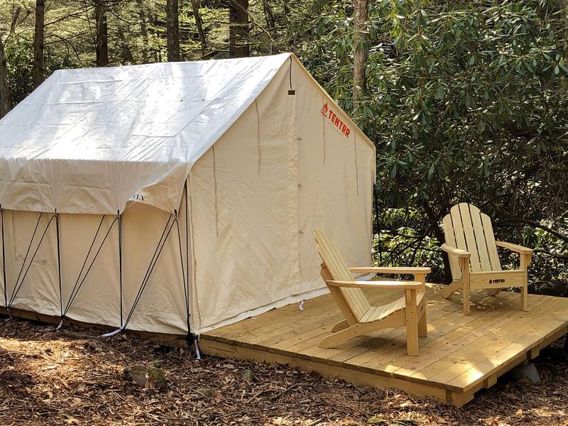 Canvas safari tent with two Adirondack chairs on a wooden platform
